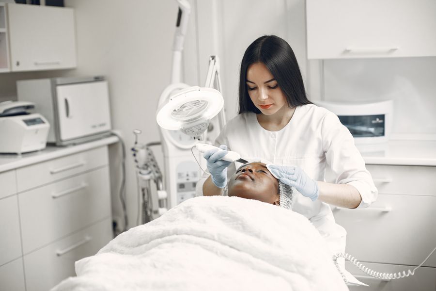 An aesthetician giving a facial treatment in a bright room